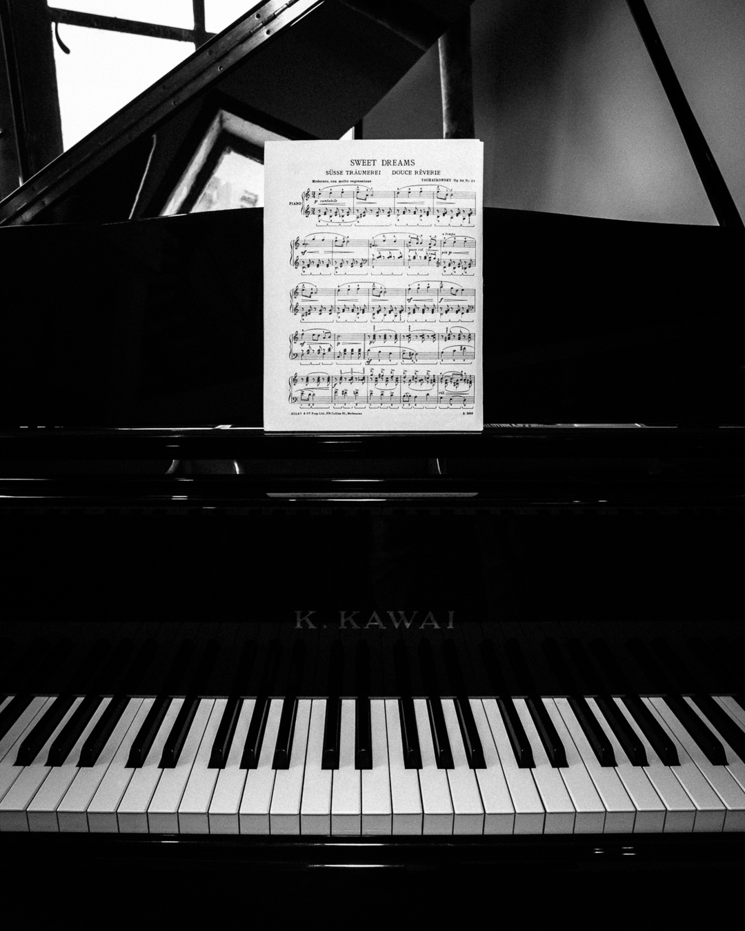 Black and white front view of the grand piano with sheet music on the stand