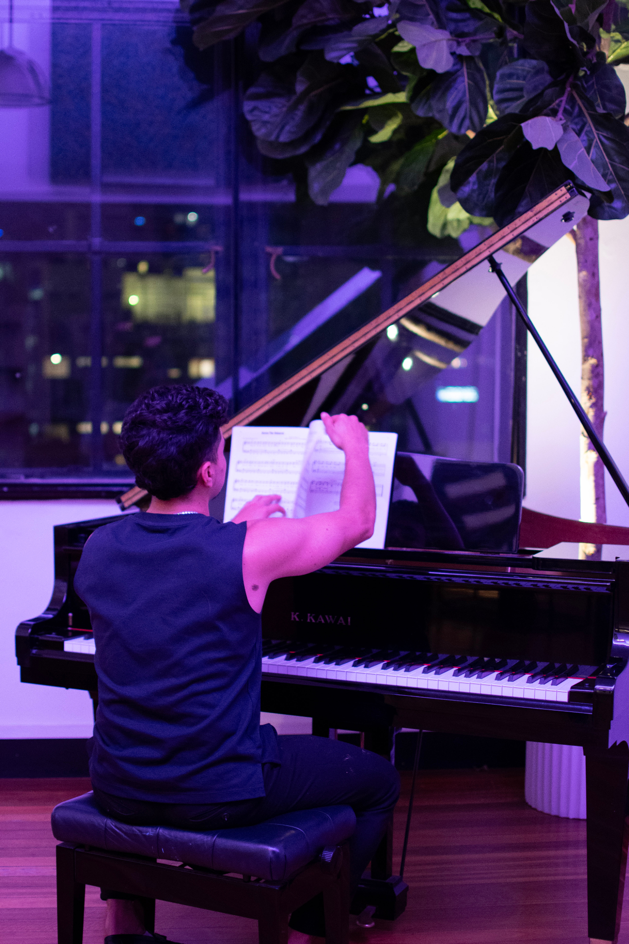 Pianist at the grand piano under violet light with the city behind