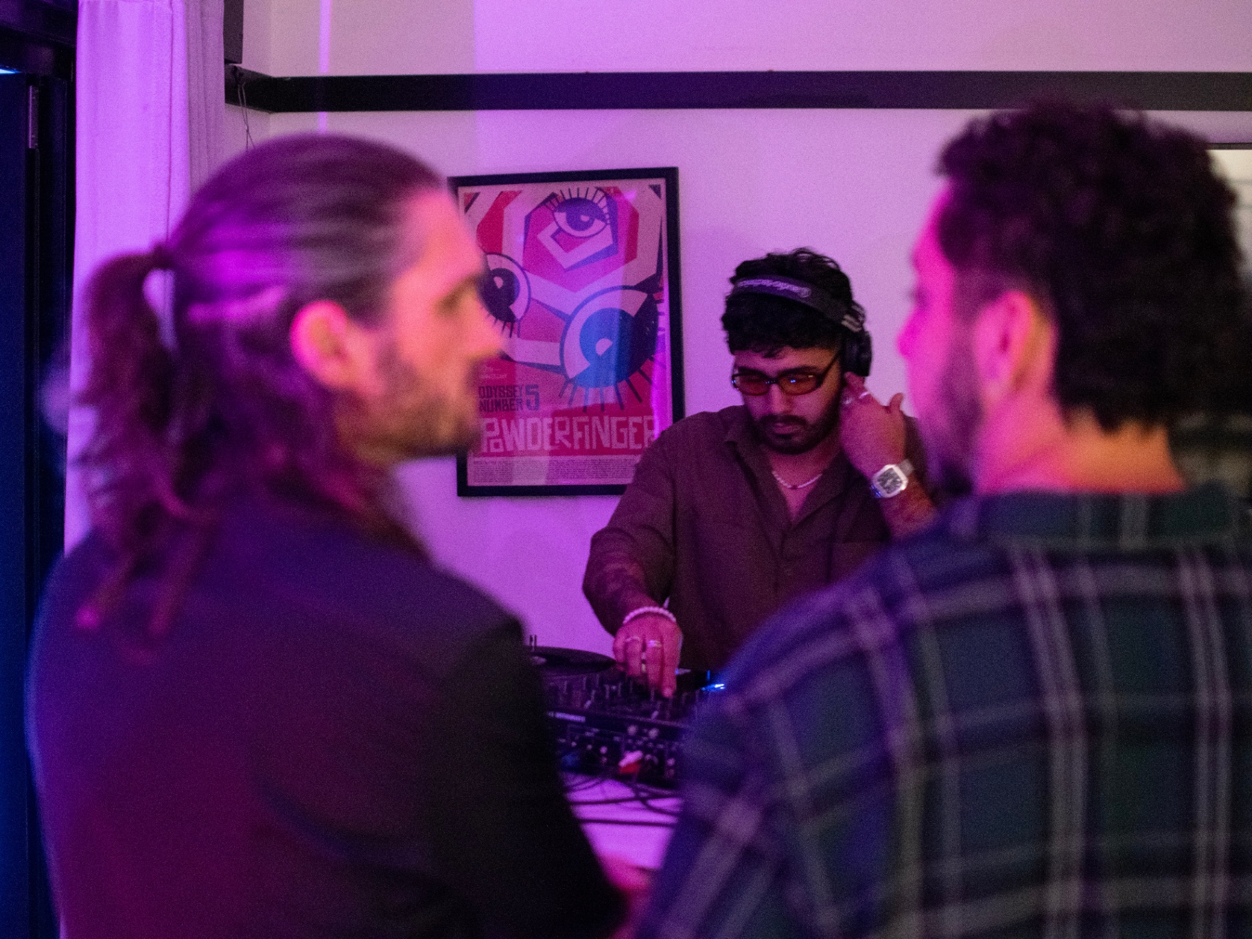 DJ behind the decks under pink and purple haze