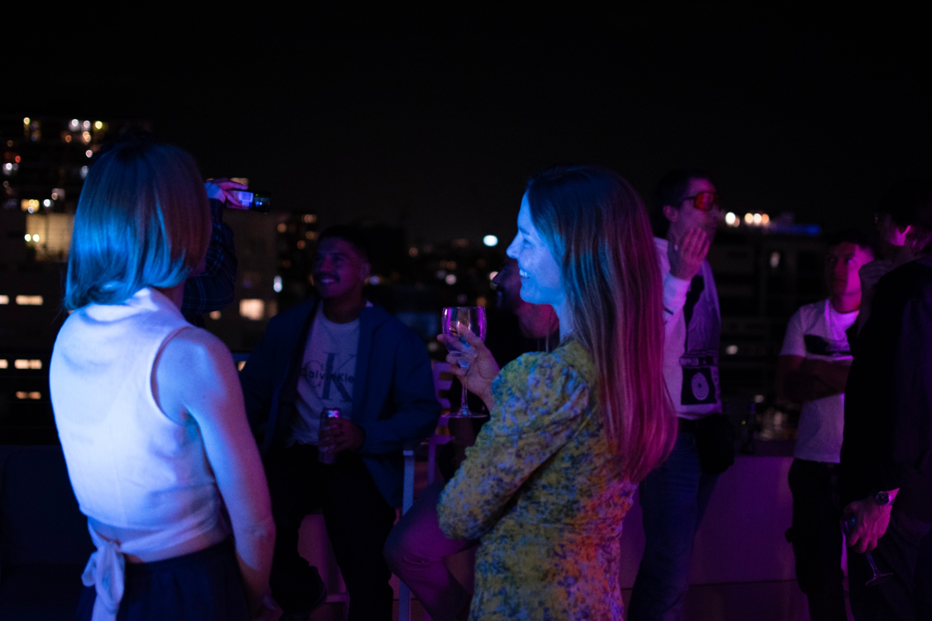 Guests laughing on the rooftop in neon light