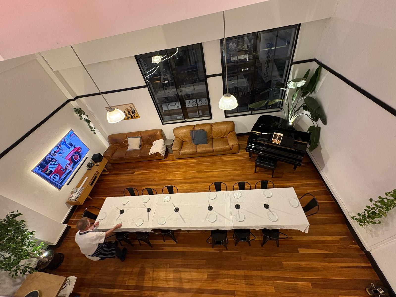View from the mezzanine — table being set beneath the heritage arch windows