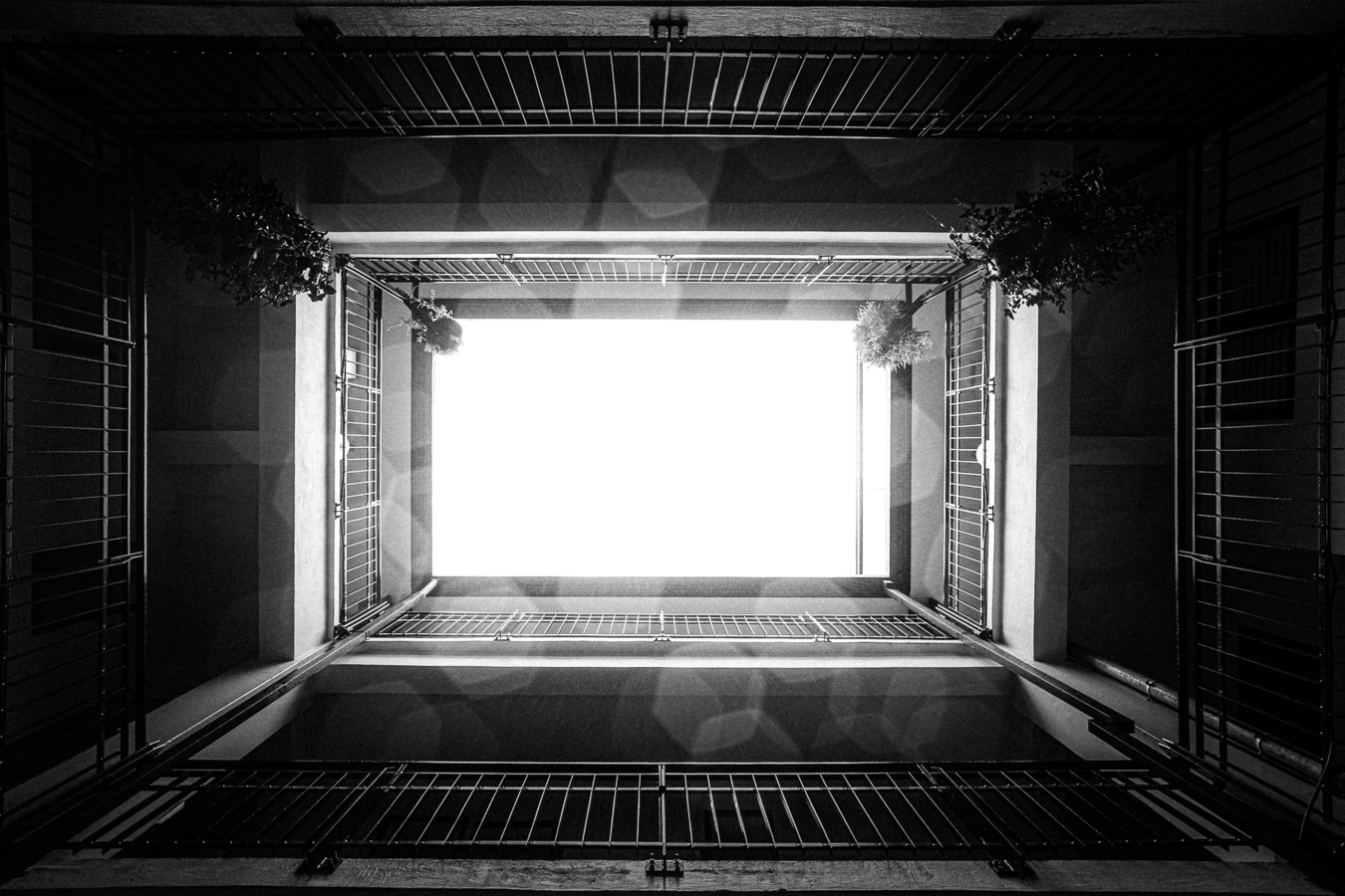 Black and white upward view through the building atrium toward the sky