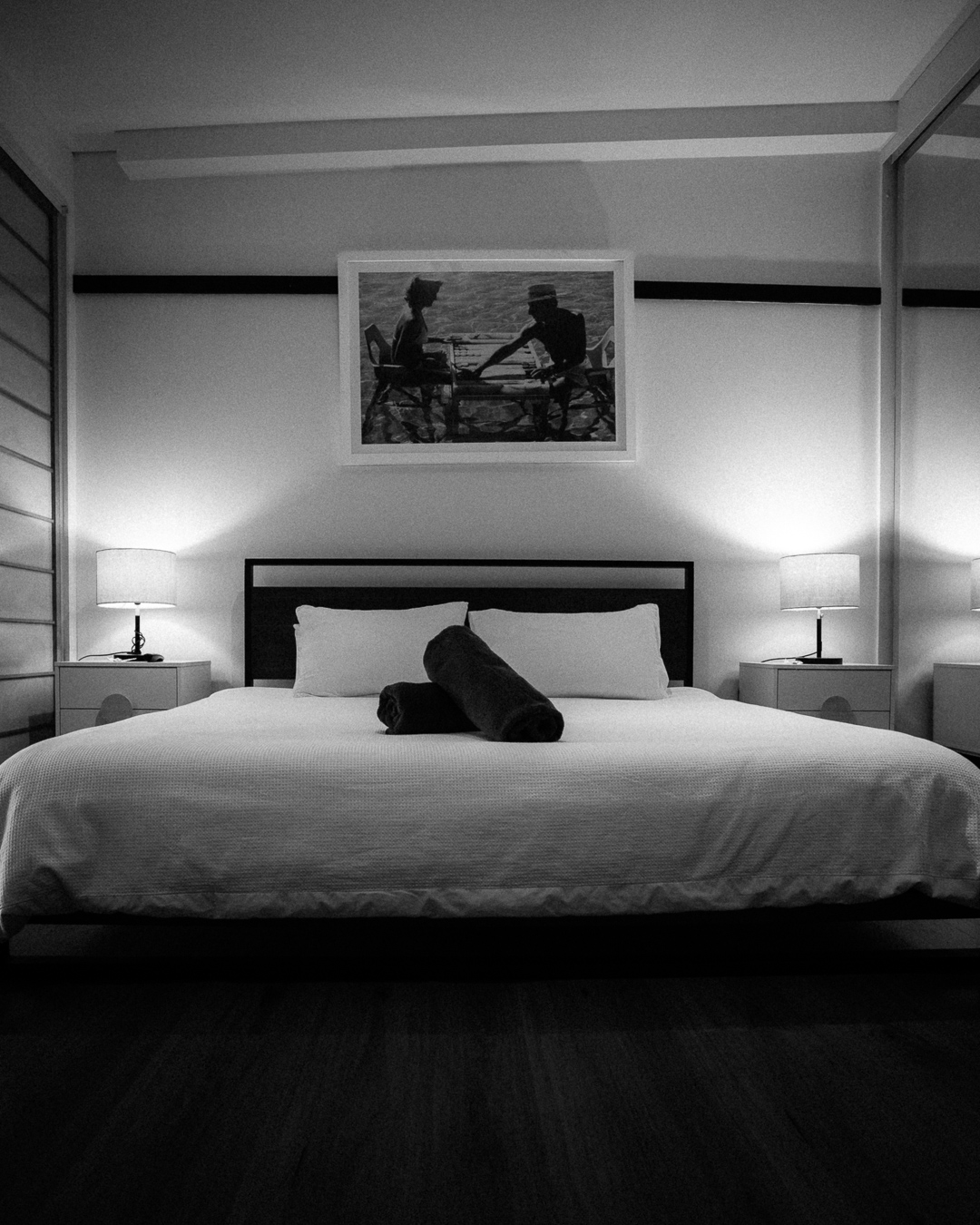 Black and white king bedroom setup with lamps and framed artwork