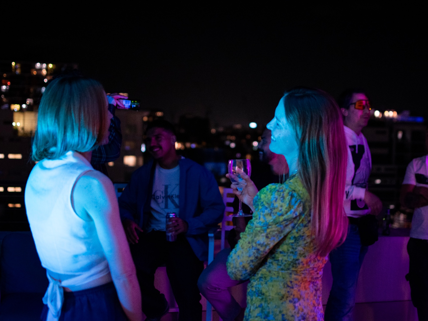 Rooftop crowd at night with the city behind