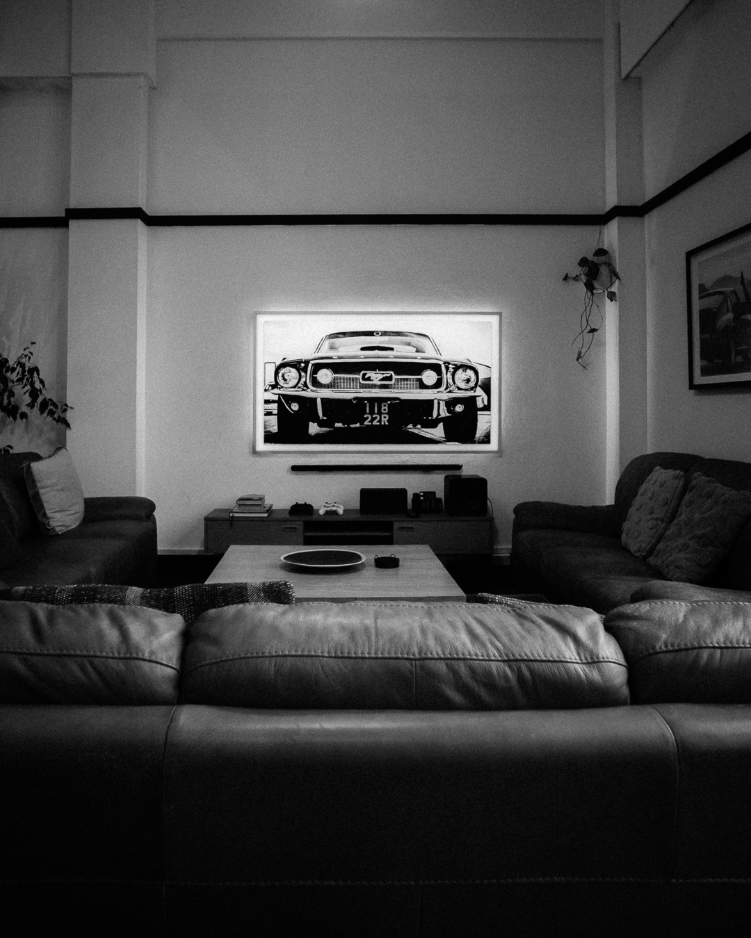 Black and white lounge room with sofas and illuminated Mustang artwork