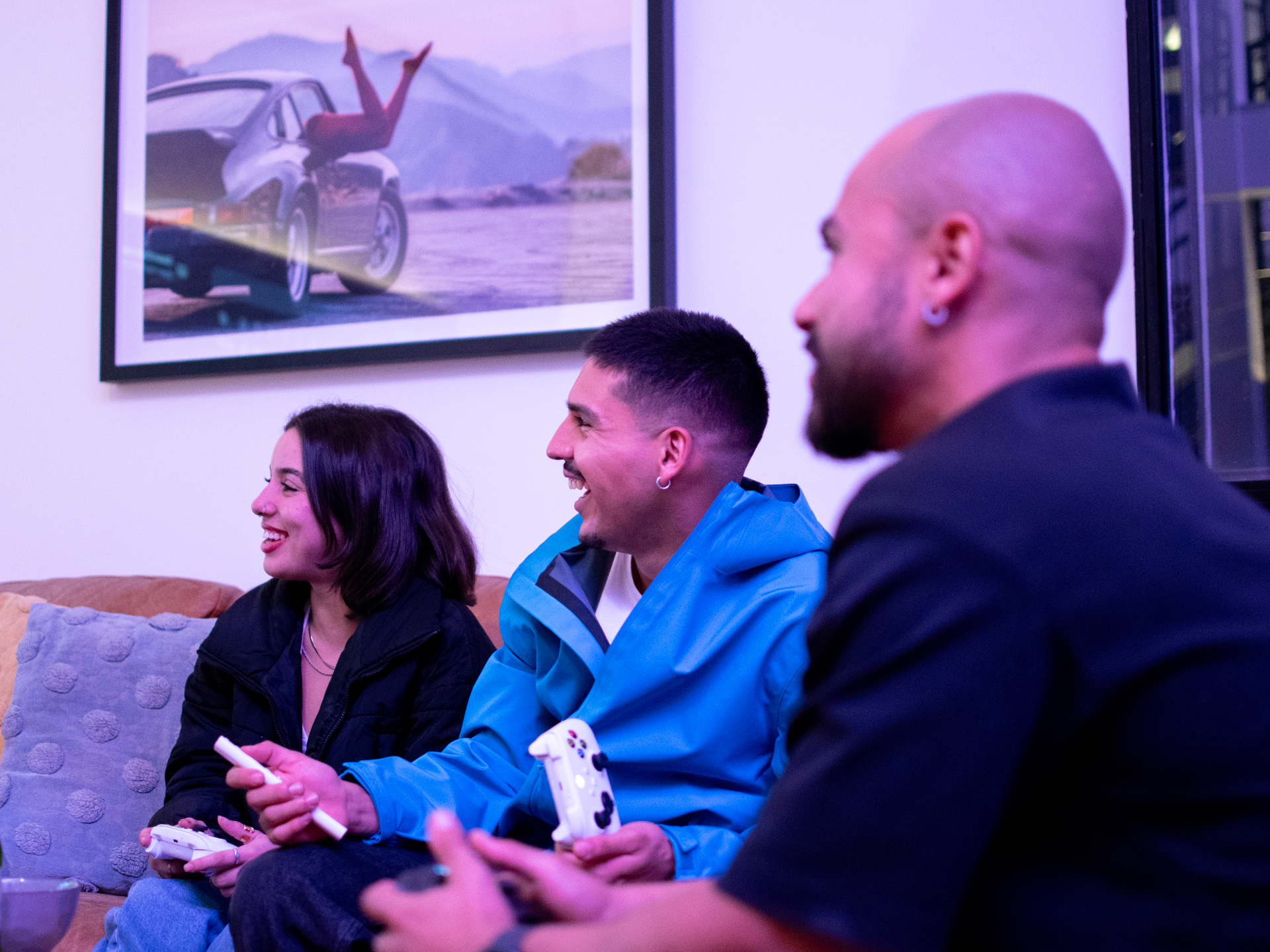 Friends laughing on the couch mid-arcade-controller tournament