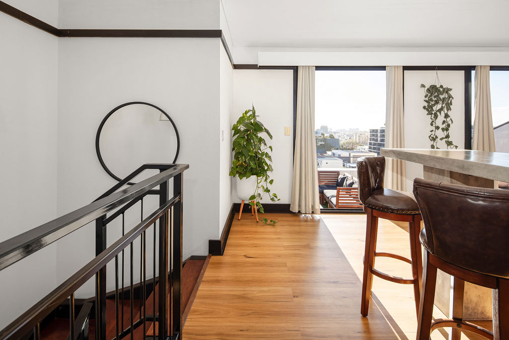 Loft landing with mirror, plants and city skyline through the window